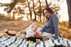 maman et bébé faisant un pique-nique sur une couverture dehors