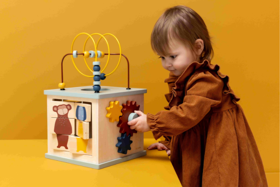 fillette jouant avec un cube d'activités en bois
