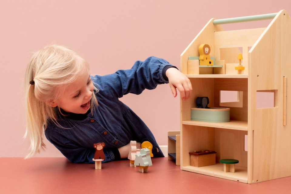 fille qui joue avec une maison de poupées en bois