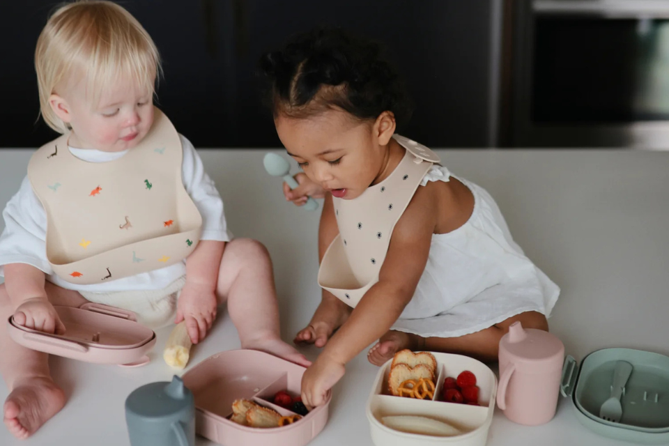 deux enfants avec bavoirs et nourriture