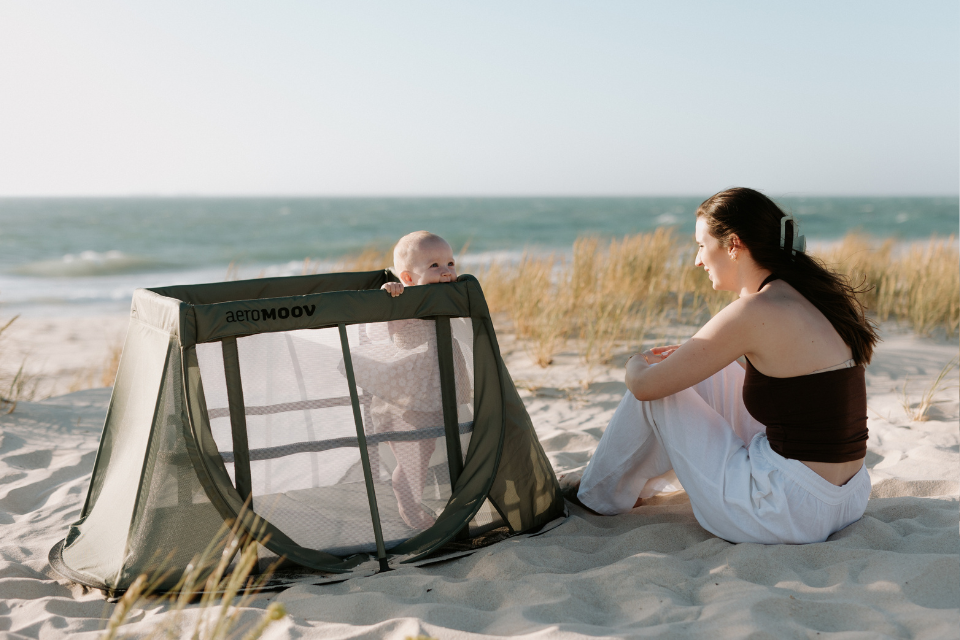 maman avec bébé dans lit parapluie à la plage