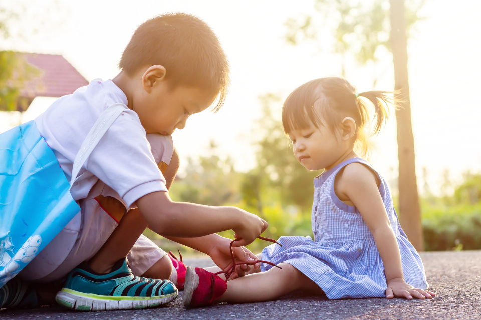 petit garçon qui fait les lacets d'une petite fille