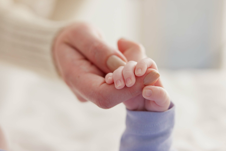 maman qui tient les doigts de bébé