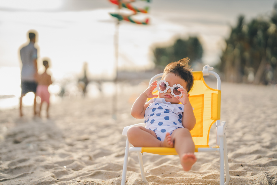 bébé avec lunettes de soleil dans chaise de plage